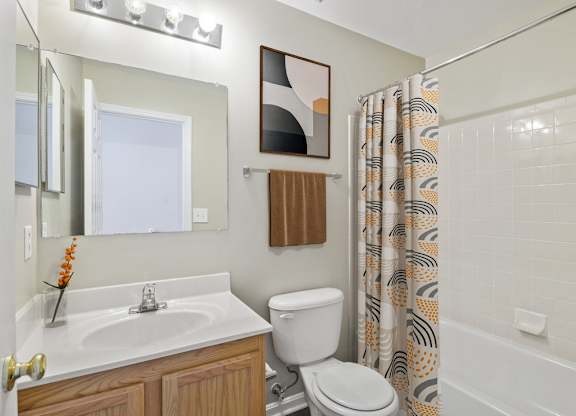 A bathroom with a white sink, toilet, and shower curtain.